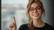 © Madlen Gray - Young woman smiling and pointing with her finger near a window