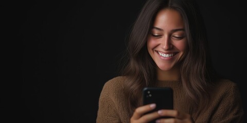 young smiling woman using mobile phone against black background