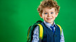 © Vilma - A young, cheerful student stands before a captivating green backdrop, portraying the excitement of going to school with a bright smile. The photo showcases a happy kid, ready to learn with a backpack.