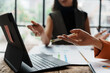 ©  NCST Studio - Businesswomen having a discussion about financial data, analyzing charts and statistics displayed on a laptop during a collaborative meeting
