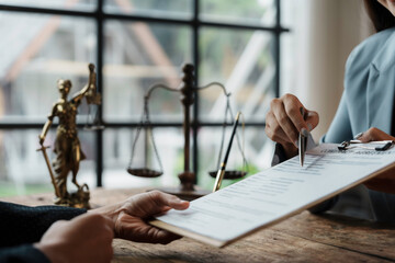 Lawyer is pointing with a pen on important details of a contract while explaining it to a client in law firm office