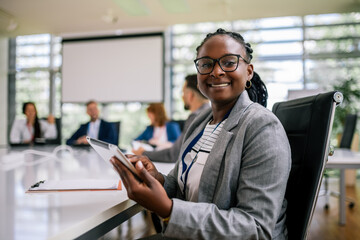 Portrait of young African American businesswoman sitting in front of her colleagues.