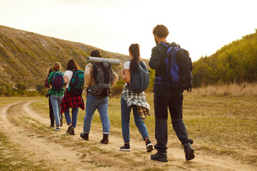 Tourist people walking rear, outdoor hiking travelling group going countryside trail, footpath. Friends enjoy happy backpack tour, nature recreational activity, natural environment journey, discovery