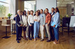 © Studio Romantic - Group of business multiethnic people men and women looking cheerful at camera and smiling indoors. Company employees or group of staff standing in office confidently. Team work concept.