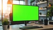 © wikkie - A modern workspace featuring a blank green screen monitor, plant, and coffee cup.