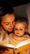 © Aleksandra - A quiet moment of reading together with mother and daughter on the couch. The daughter is holding a favorite picture book while the mother reads aloud.