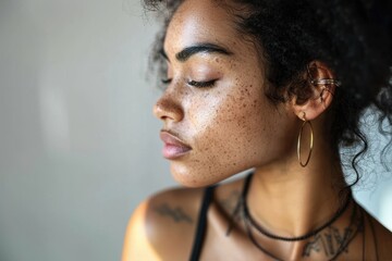 A serene close-up profile of a young woman with curly hair and gold hoop earrings. The soft lighting emphasizes her natural beauty and calm demeanor.