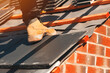© Iryna - A skilled worker installing roof tiles on a sunny day in a residential area, showcasing craftsmanship and dedication
