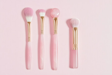 Three makeup brushes on pink background.