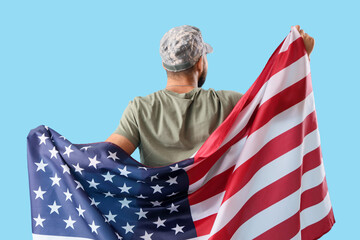 Male soldier with USA flag on blue background, back view. Veterans Day celebration