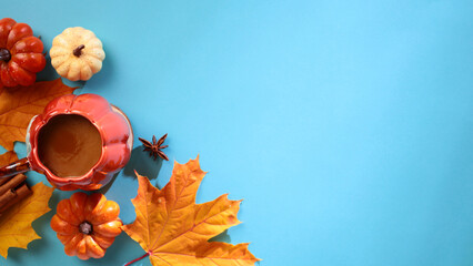 Wall Mural - Autumn, fall flat lay composition. Top view cup of coffee, pumpkins, autumn leaves on blue background.