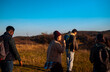 © Zoran Zeremski - Group of friends hiking together on hill peak at sunset.