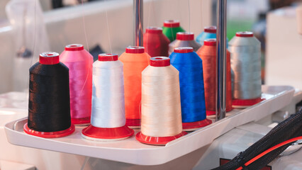 Aufkleber - A white tray with a bunch of colorful spools of thread. The spools are of different colors and sizes, and they are arranged in a neat row. Concept of organization and order