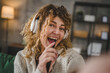 © Miljan Živković - One woman with headphones at home listen music online happy smile sing
