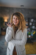© Miljan Živković - woman with curly hair at home use mobile phone smartphone have a call