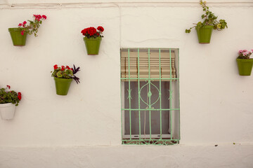 Flowers in patterned ceramic vases fixed to the wall of an old house. Decor of the old town of Nerja in Spain