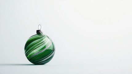   A green glass ornament sits atop a white table alongside a black and white striped ornament