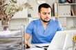 © JackF - Skillful man physician sitting at table in his office and using laptop.