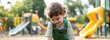 © Jiraporn - Curly-haired boy playing in dirt at a playground, joyful expression.