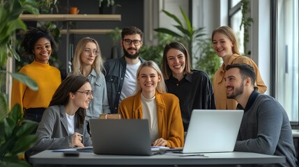 Wall Mural - Diverse group of young professionals gathered around a laptop, smiling and engaged in conversation.