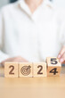 © Jo Panuwat D - 2024 year change to 2025 year block with dartboard icon. Goal, Target, Resolution, strategy, plan, Action, mission, motivation, and New Year start concepts