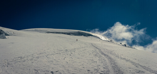 Trodden path in snow high mountain glacier Mont Blanc with small hiker clear day blue sky