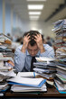 © Emanuel - Overworked employee sitting at a desk with head in hands, surrounded by piles of paperwork