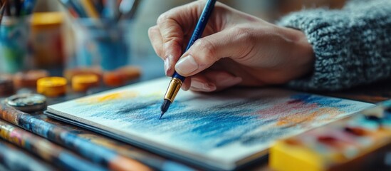 Poster - a hand using a brush to paint on a watercolor paper.