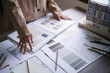 © snowing12 - Female architect choosing color swatch sample to design interior of building project on blueprint