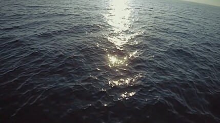 A close-up of the ocean's surface, with the sun glinting off the water.