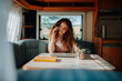 © Halfpoint - Young beautiful woman is on a camping trip in nature, sitting in her caravan making phone call. Caravan as homeoffice, working remotely.