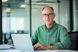 © 为轩 张 - Middle-aged man with glasses working on a laptop at an office desk, blurred glass wall background, wide-angle professional photograph.