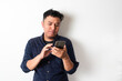© rukuta.project - Adult Asian young man looking to his mobile phone