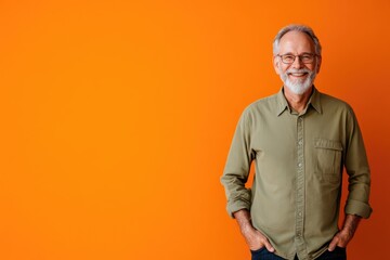 Senior male presenter, smiling with one hand in pocket, standing against a solid orange background with space for text