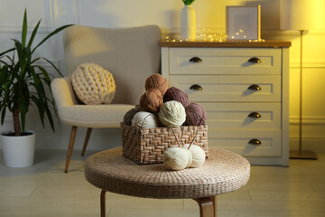 Poster - Wicker basket with colorful yarns and knitting needles on coffee table in cozy room