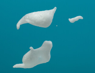 White bubble foam fly in many shape form and splashing in air. Bubble foam use to clean wash toilet kitchen bathroom. Blue background isolated