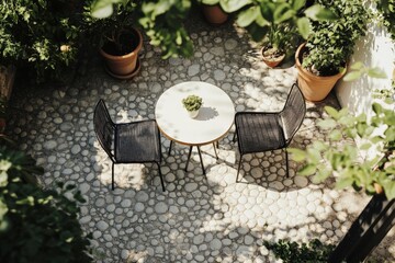 An aerial view of a cozy patio setup featuring a round table and two chairs amidst a rustic setting with potted plants, creating a warm, intimate atmosphere.