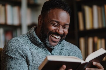 young man reading a book and laughing
