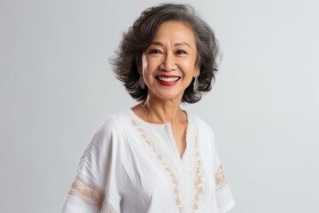 Wall Mural - Portrait of a happy senior asian woman smiling over gray background