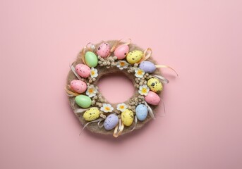 Beautiful easter wreath made of colorful eggs and flowers lying on pink background with copy space