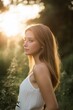 © StockUp - A beautiful young woman stands in the sunset, surrounded by lush greenery, exuding serenity and peace.