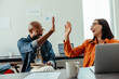 © (JLco) Julia Amaral - Co-workers celebrating success with a high-five in a modern office setting