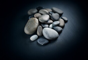 Poster - Smooth grey and black stones on a dark surface.