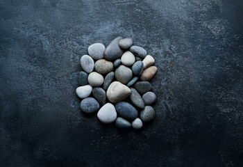 Poster - A cluster of smooth, grey, and white stones are gathered together on a dark, textured background.