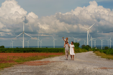 Family and travel, behind is a windmill, renewable energy source, environmental sustainability concept