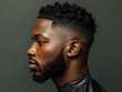 © Tanakorn - Profile of a Black Man with a Tapered Haircut and a Short Beard, Wearing a Black Barber Cape Against a Gray Background