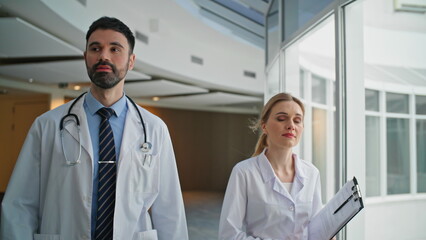 Two doctors walking hospital greeting colleague closeup. Medical team together