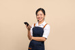 © PBXStudio - Portrait of cute Asian girl in apron using smartphone on beige background
