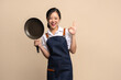 © PBXStudio - Beautiful Asian woman in apron with pan on background