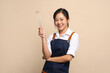 © PBXStudio - Beautiful Asian woman in apron holding separate egg beater on beige background. Ready for cooking.